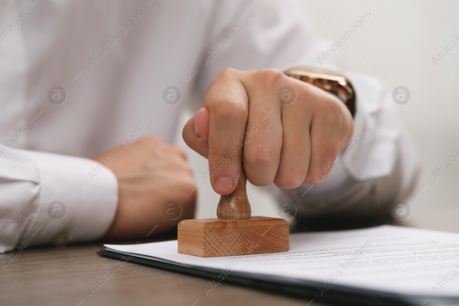 Photo of Man stamping document at wooden table, closeup