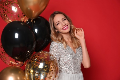 Photo of Happy woman with air balloons on red background. Christmas party