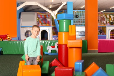 Photo of Cute child playing with colorful building blocks indoors