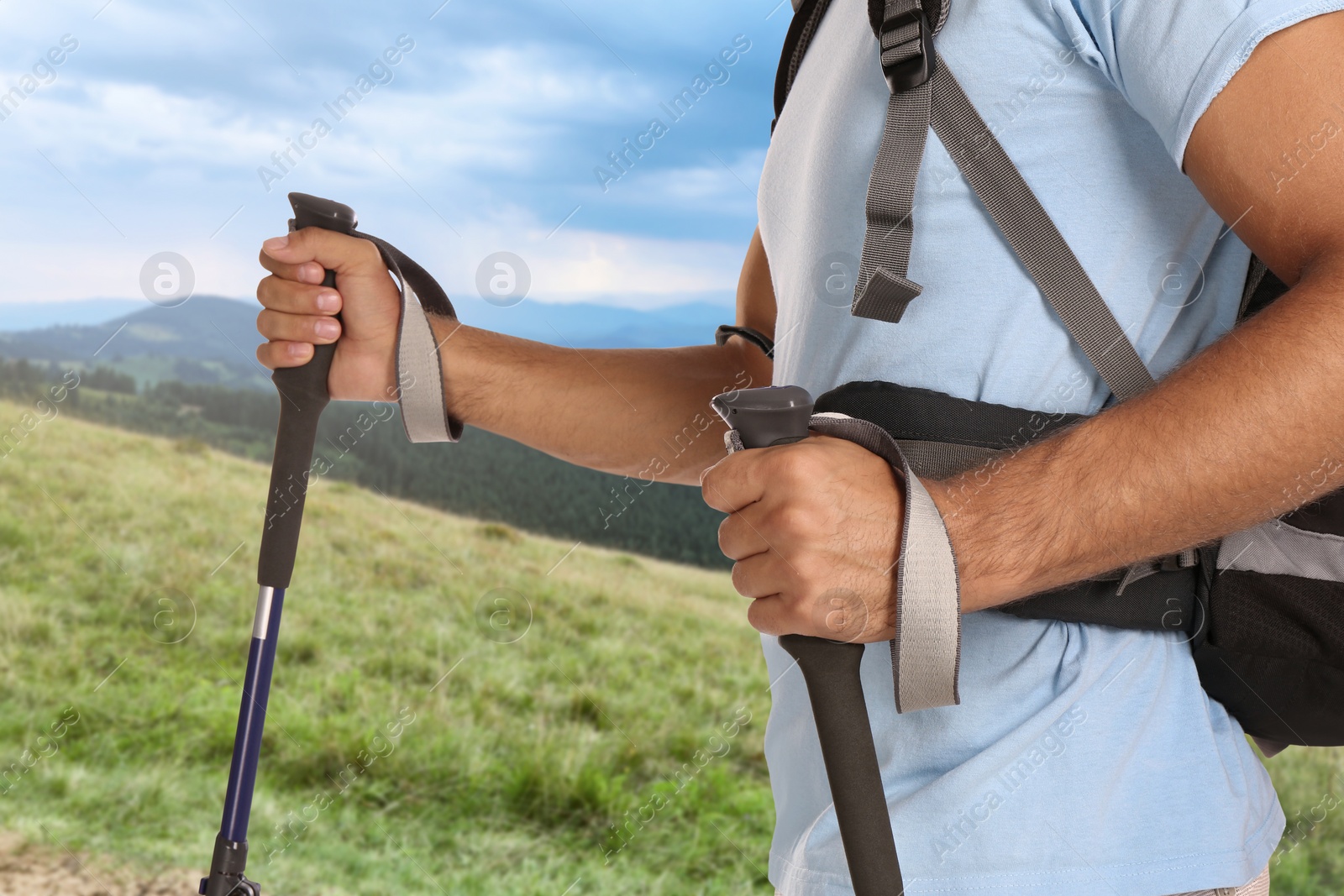 Image of Man with backpack and trekking poles in mountains on sunny day, closeup