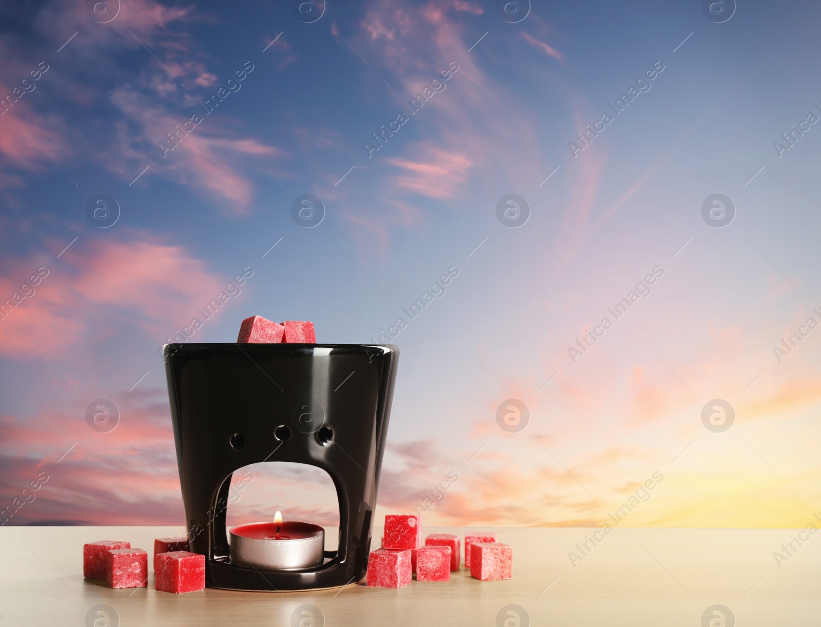 Image of Stylish aroma lamp with wax cubes on wooden table outdoors at sunset, space for text