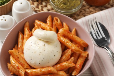 Photo of Bowl of delicious pasta with burrata and tomato sauce on table, closeup