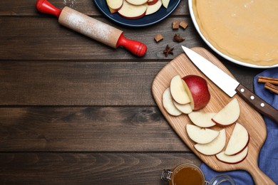 Photo of Cut fresh apple with knife, board on wooden table, flat lay and space for text. Baking pie
