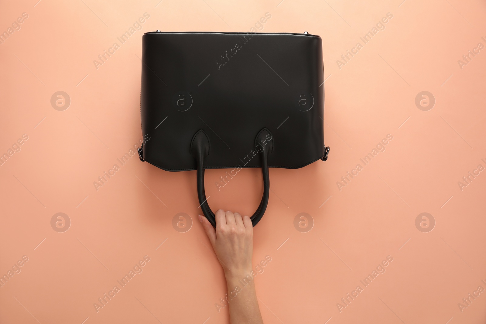 Photo of Woman holding stylish bag on beige background, closeup