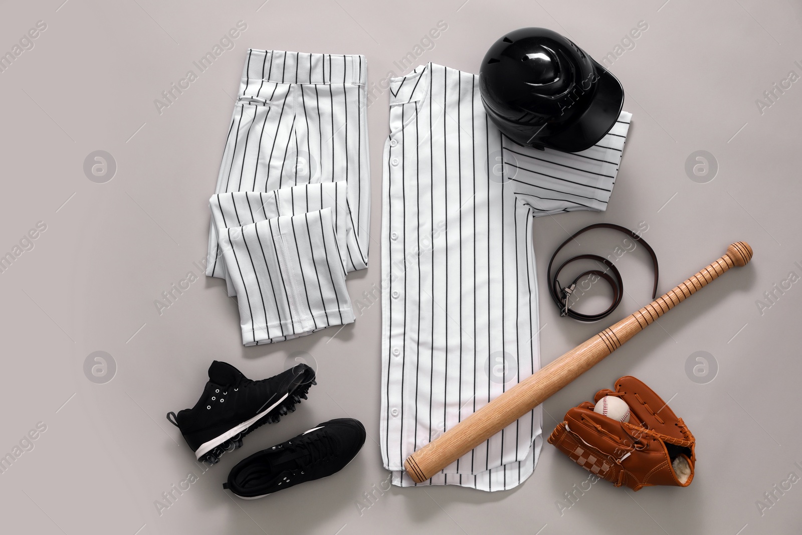 Photo of Baseball uniform and other sports equipment on white background, flat lay