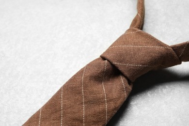 One striped necktie on light textured table, above view