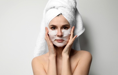 Photo of Beautiful woman with cotton face and eye masks against light background