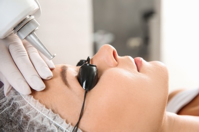 Photo of Young woman undergoing laser removal of permanent makeup in salon. Eyebrow correction