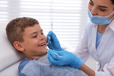 Photo of Dentist examining little boy's teeth in modern clinic