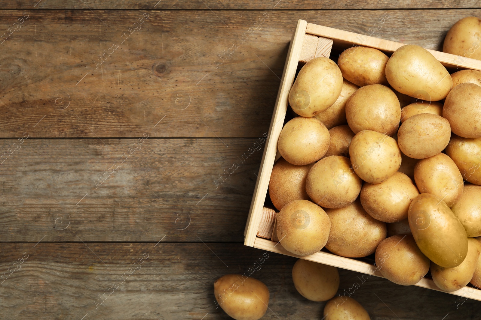 Photo of Raw fresh organic potatoes on wooden background, top view. Space for text