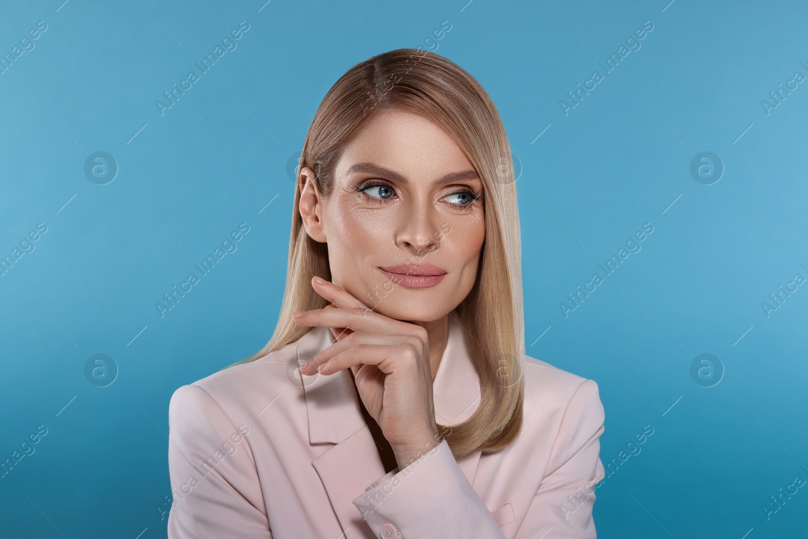 Image of Portrait of stylish attractive woman with blonde hair on light blue background