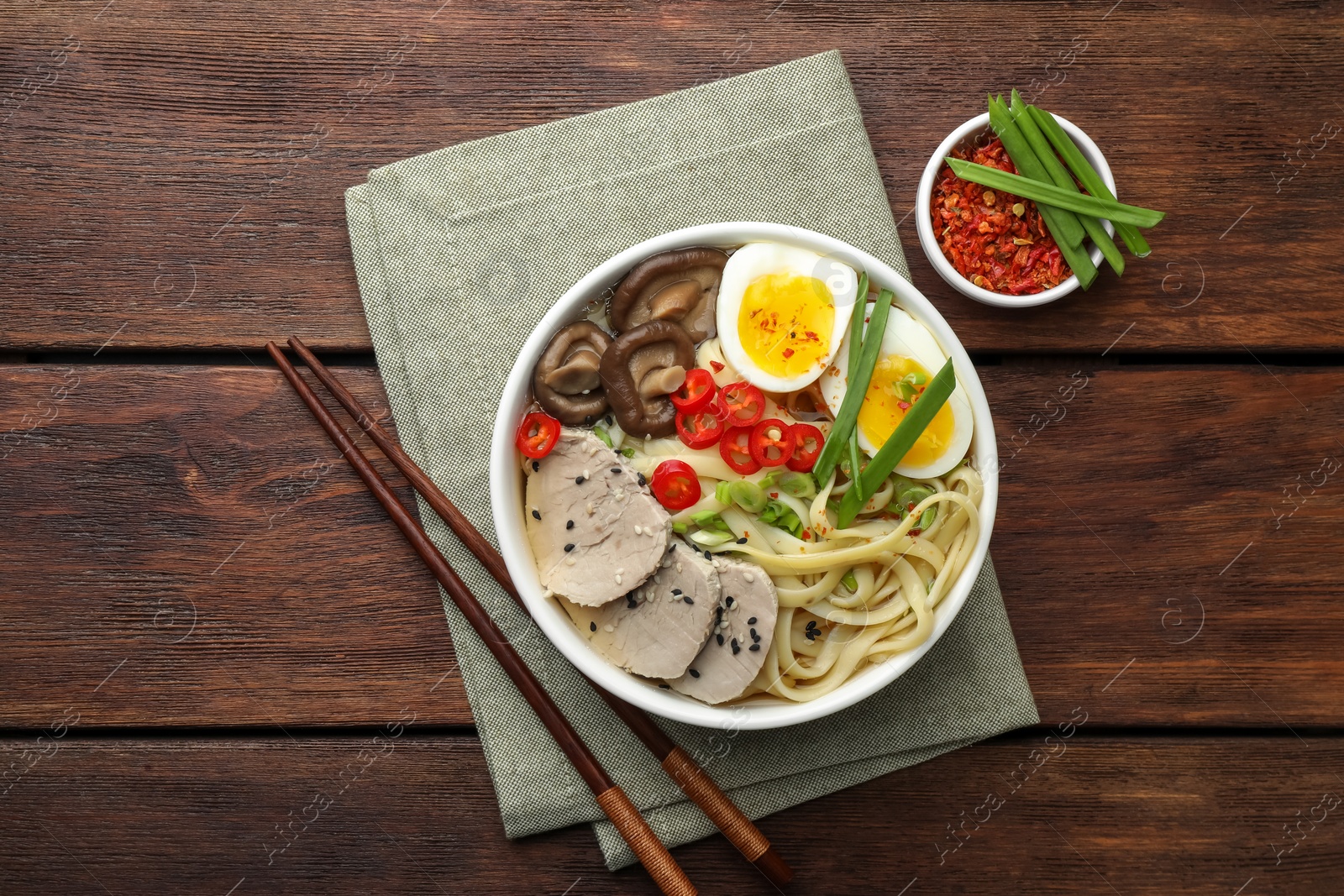 Photo of Delicious ramen with meat in bowl served on wooden table, flat lay. Noodle soup