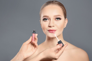 Artist applying makeup onto woman's face on light grey background