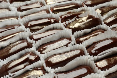 Many delicious eclairs with chocolate icing as background