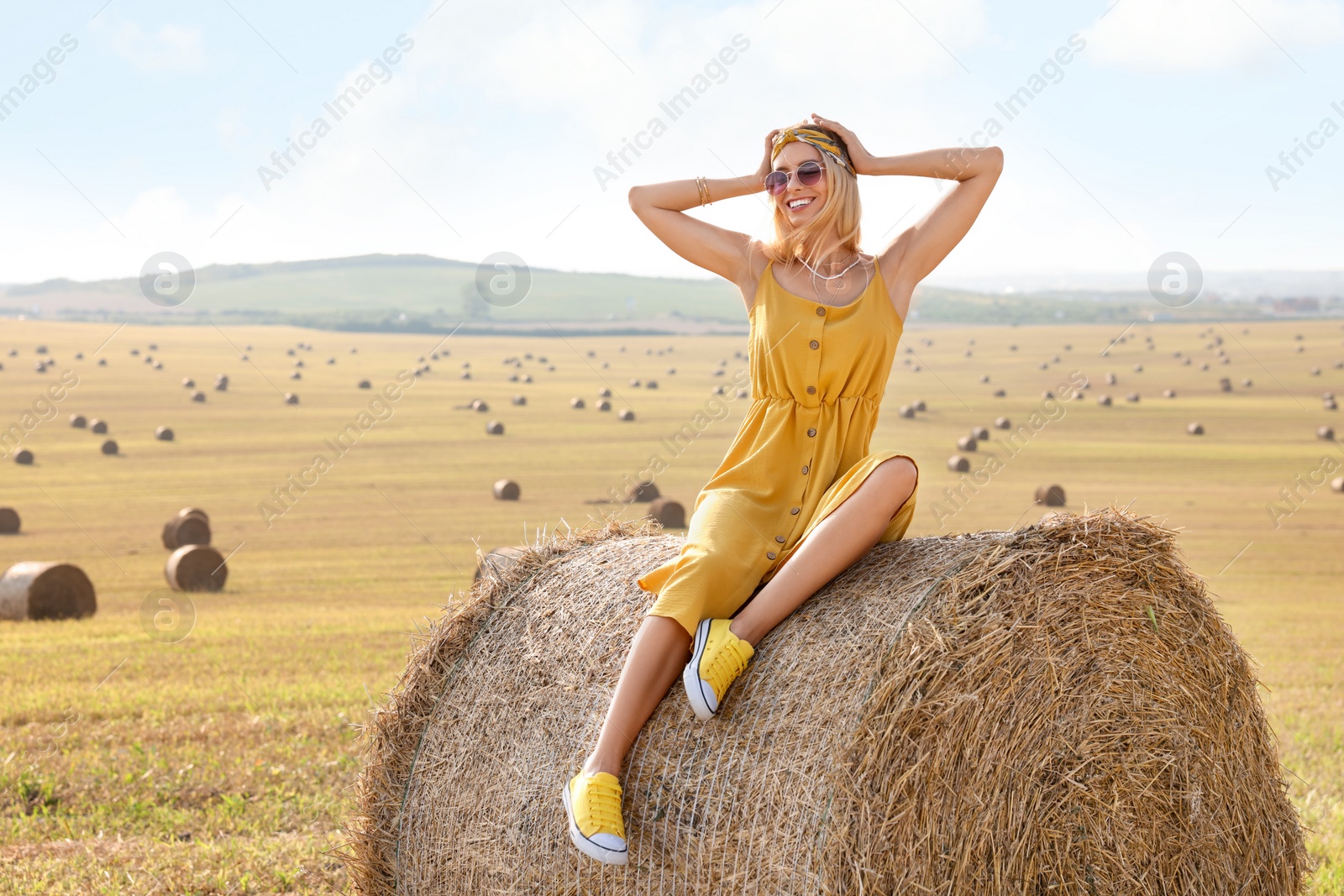 Photo of Beautiful hippie woman on hay bale in field, space for text