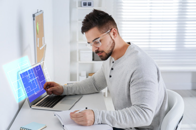 Image of Engineer at work. Young man projecting house in office