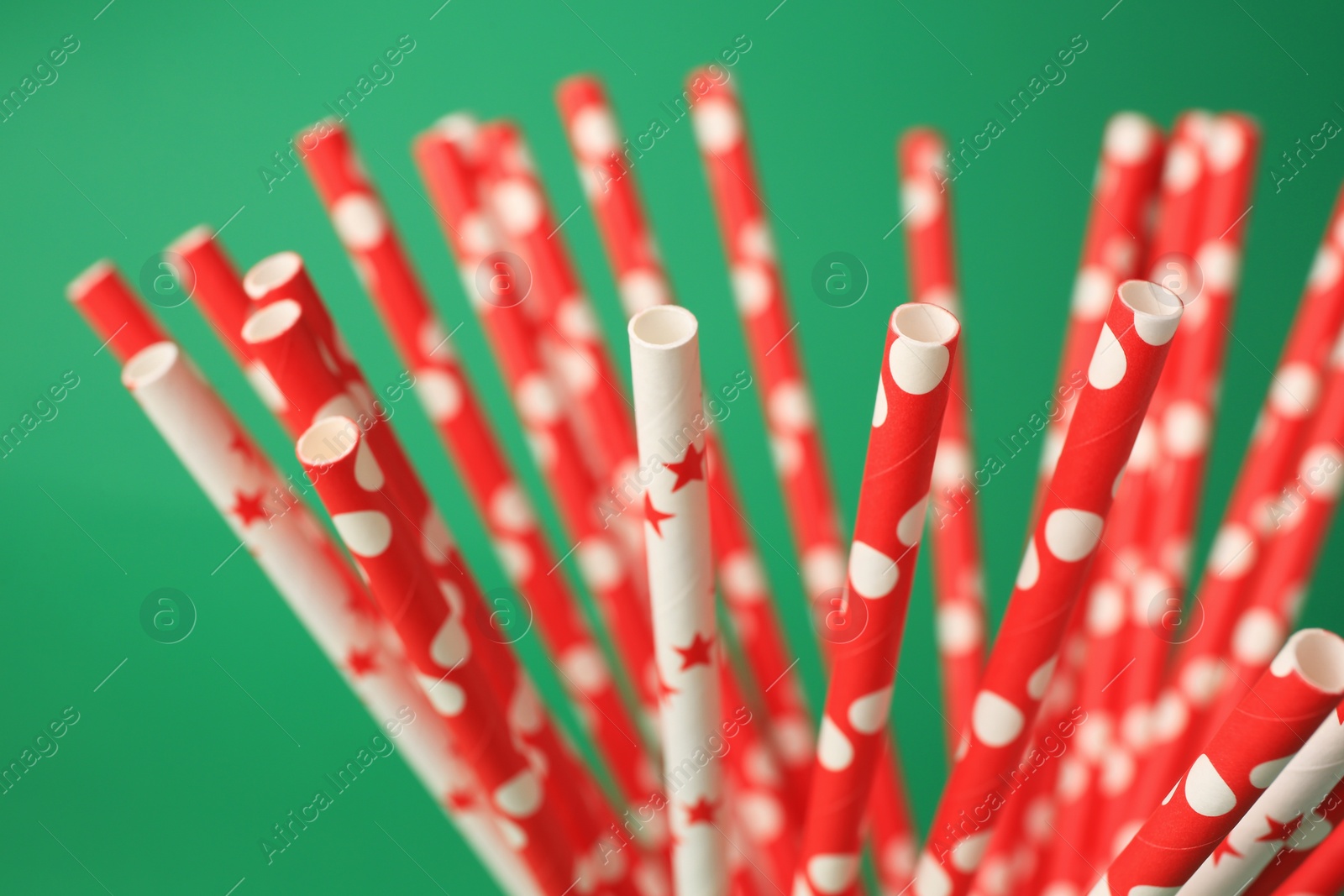 Photo of Bright paper drinking straws on green background, closeup