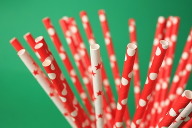 Bright paper drinking straws on green background, closeup