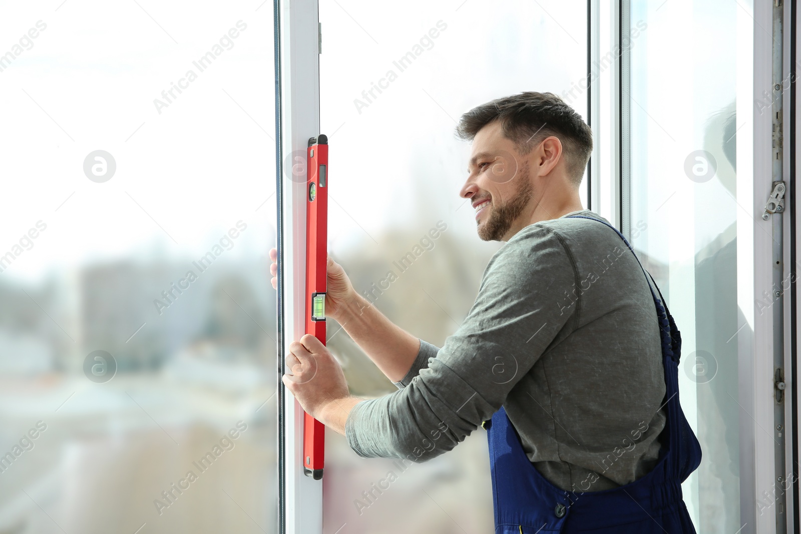 Photo of Construction worker using bubble level while installing window indoors
