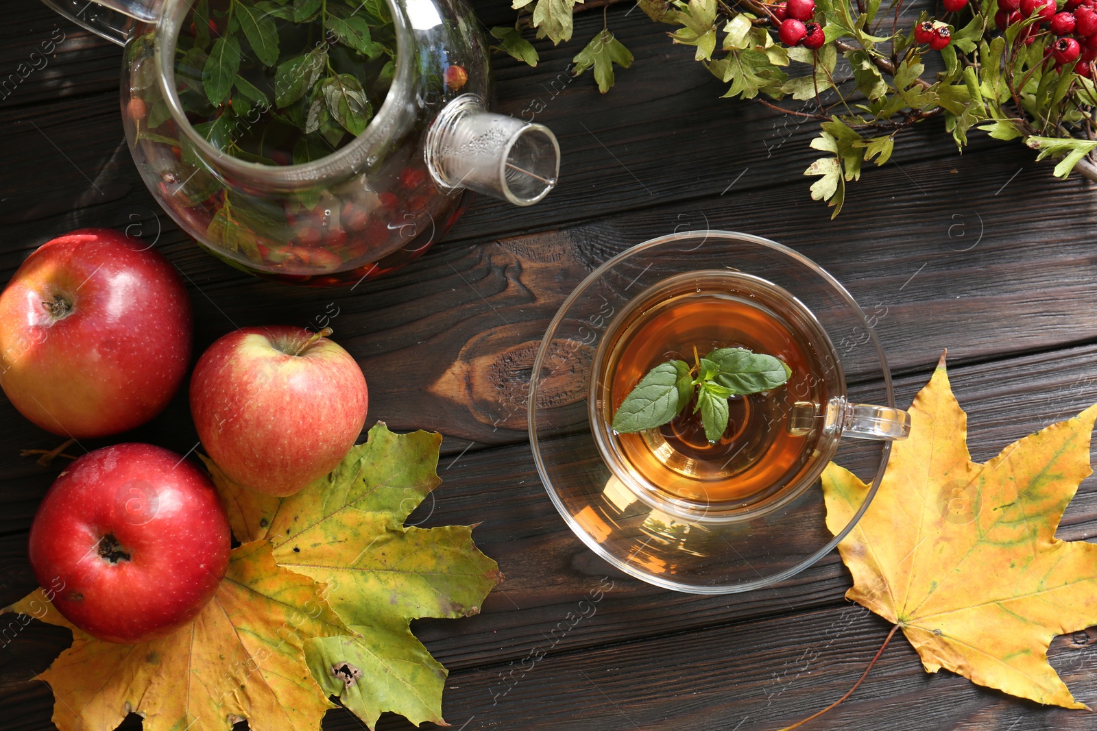 Photo of Hot tea, apples, dry leaves and viburnum on wooden table, flat lay. Autumn atmosphere