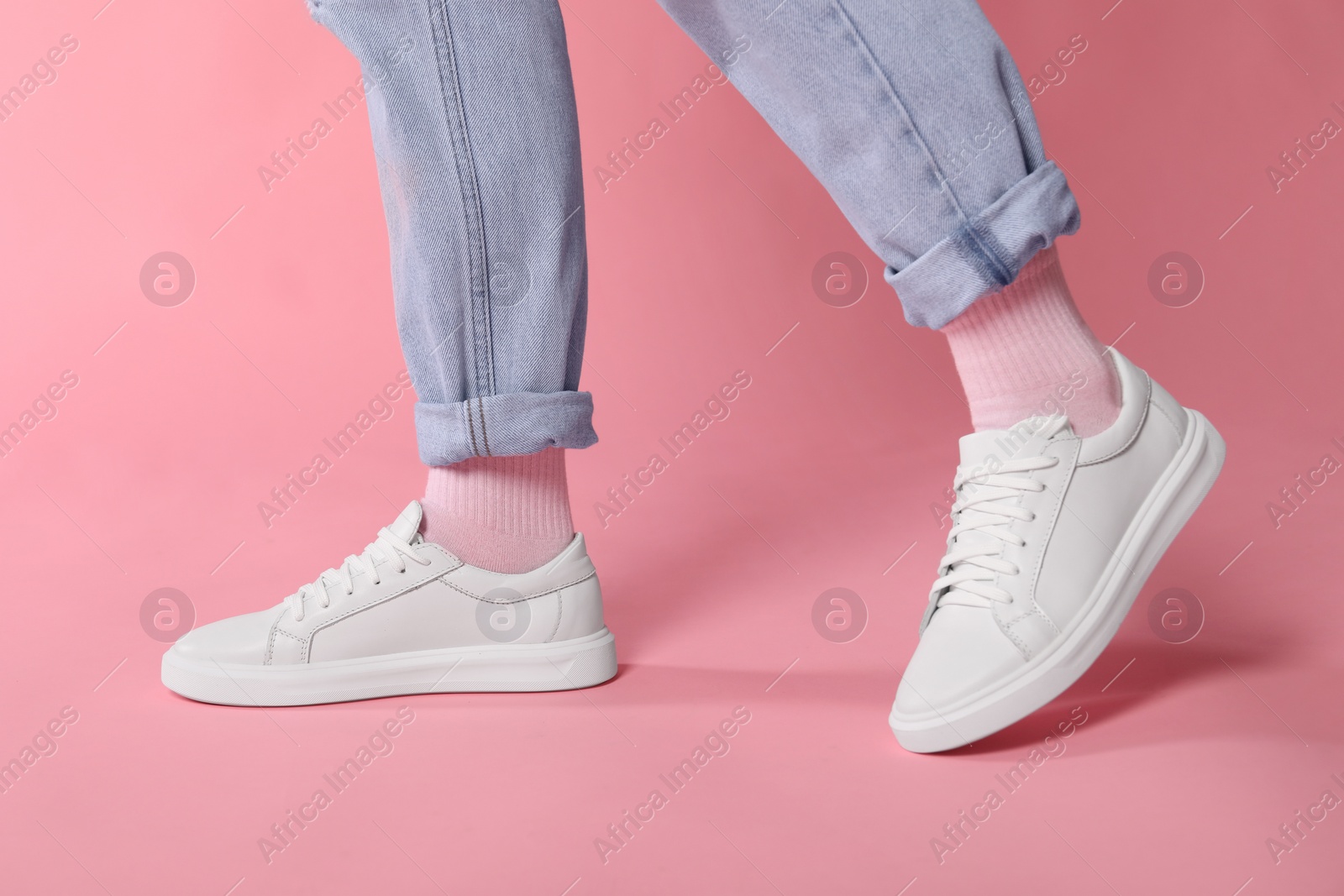 Photo of Woman wearing stylish white sneakers on pink background, closeup