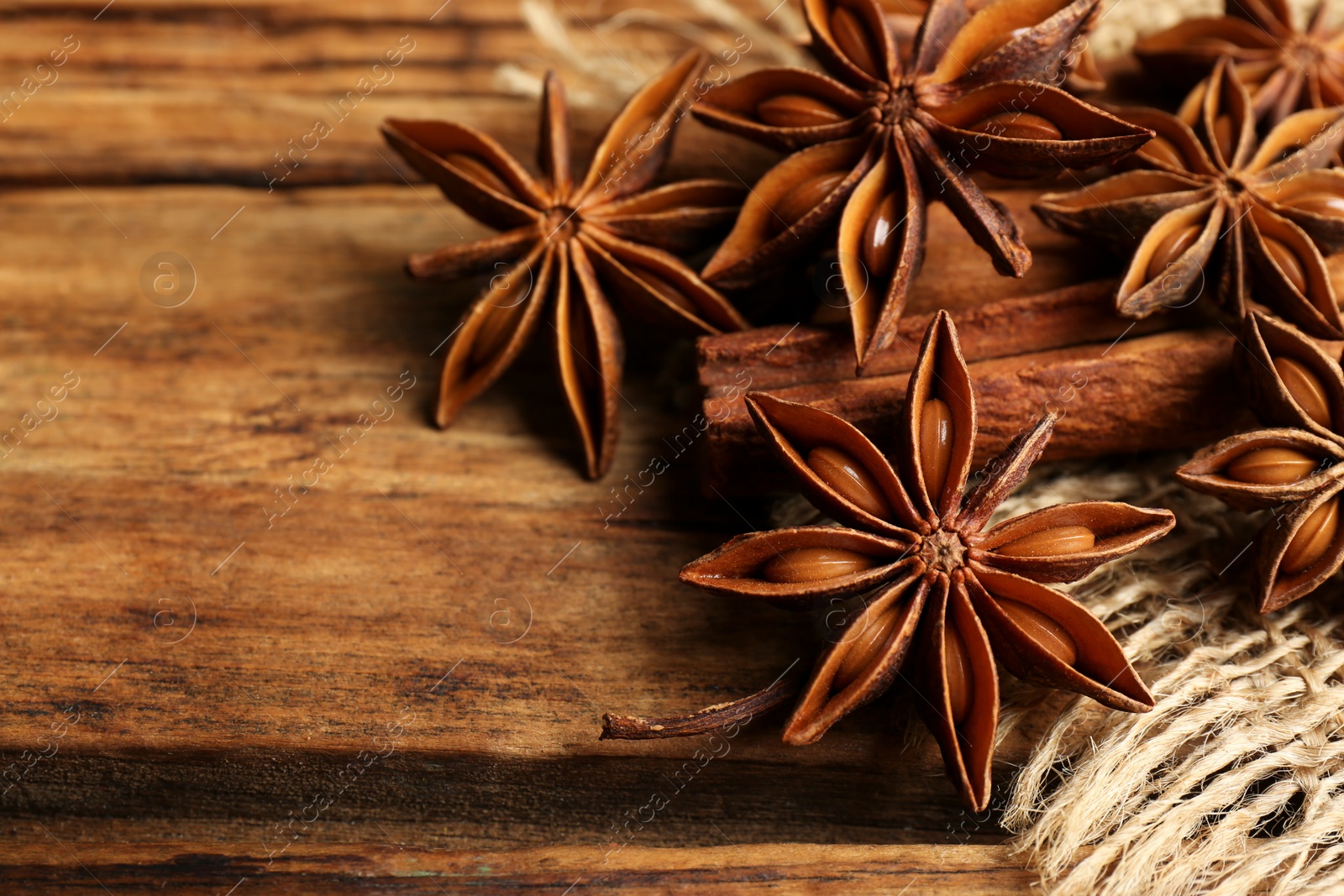 Photo of Aromatic anise stars and cinnamon sticks on wooden table, closeup