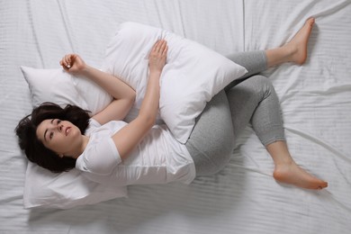 Photo of Young woman suffering from insomnia in bed, top view