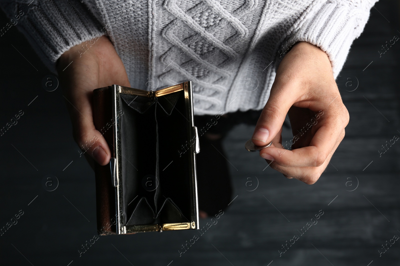 Photo of Poor woman holding empty wallet and coin on wooden background, closeup