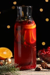 Photo of Glass bottle of aromatic punch drink, fir and ingredients on wooden table