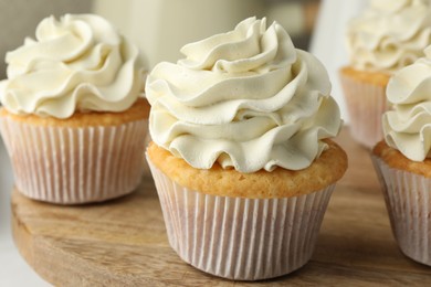 Tasty vanilla cupcakes with cream on table, closeup