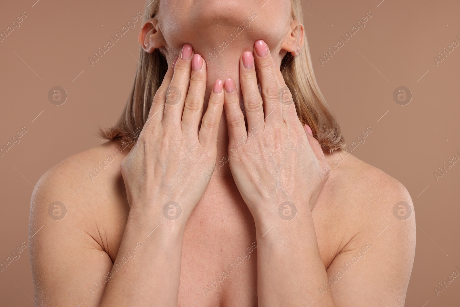 Photo of Beautiful woman touching her neck on beige background, closeup