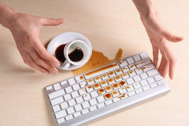 Photo of Woman with coffee spilled over computer keyboard at wooden table, above view