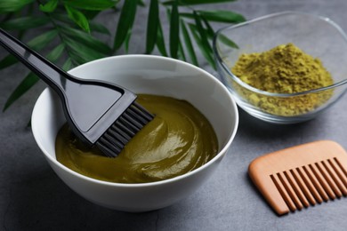 Bowl of henna cream, brush and comb on light grey table, closeup. Natural hair coloring