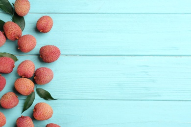 Photo of Fresh ripe lychee fruits on light blue wooden table, flat lay. Space for text