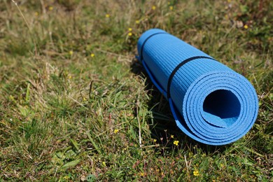 Photo of Rolled blue soft sleeping pad on grass, space for text