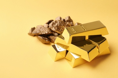 Photo of Gold nuggets and ingots on color background