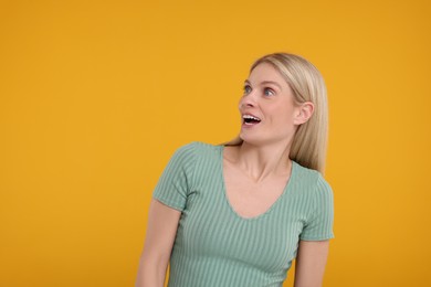 Portrait of happy surprised woman on yellow background, space for text
