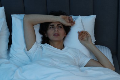 Young woman suffering from headache in bed at night