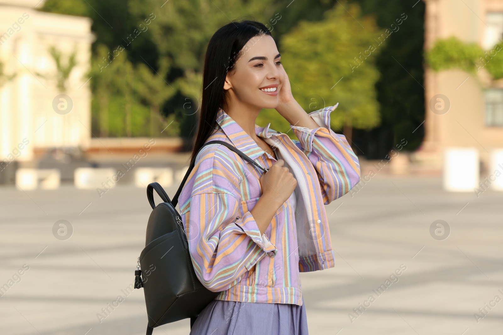 Photo of Beautiful young woman with stylish black backpack on city street