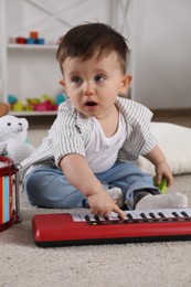 Photo of Cute little boy playing toy piano at home