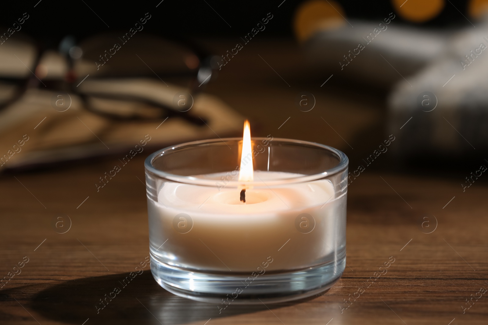 Photo of Burning candle in glass holder on wooden table