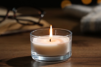 Photo of Burning candle in glass holder on wooden table