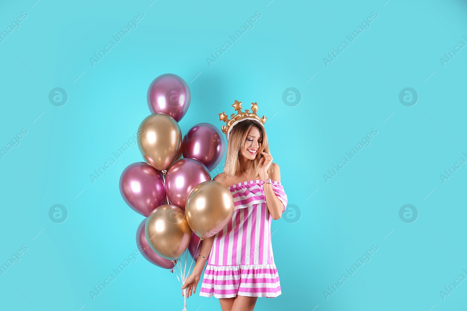 Photo of Young woman with crown and air balloons on color background