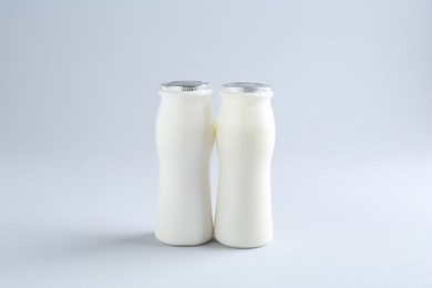 Photo of Tasty yogurt in bottles on light grey background