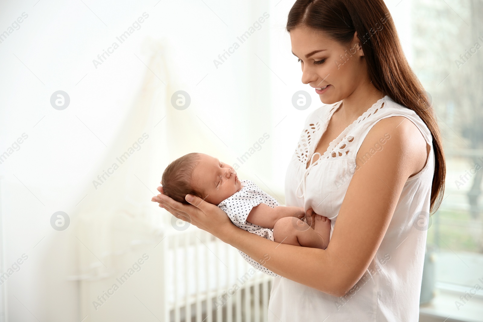 Photo of Young woman holding her newborn baby at home. Space for text