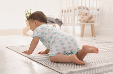 Photo of Cute baby crawling on floor at home, back view