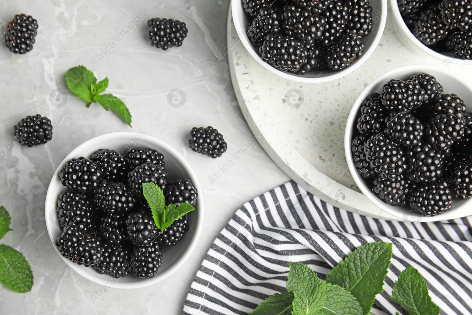 Photo of Flat lay composition of tasty blackberries on grey marble table