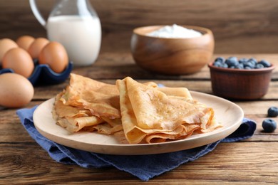 Photo of Delicious crepes served on wooden table. Space for text