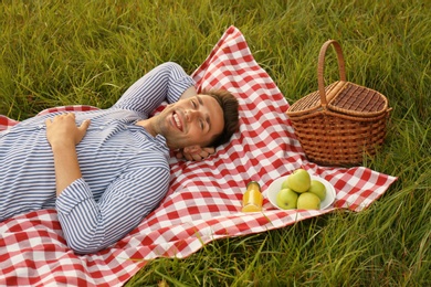 Young man lying on picnic blanket in park