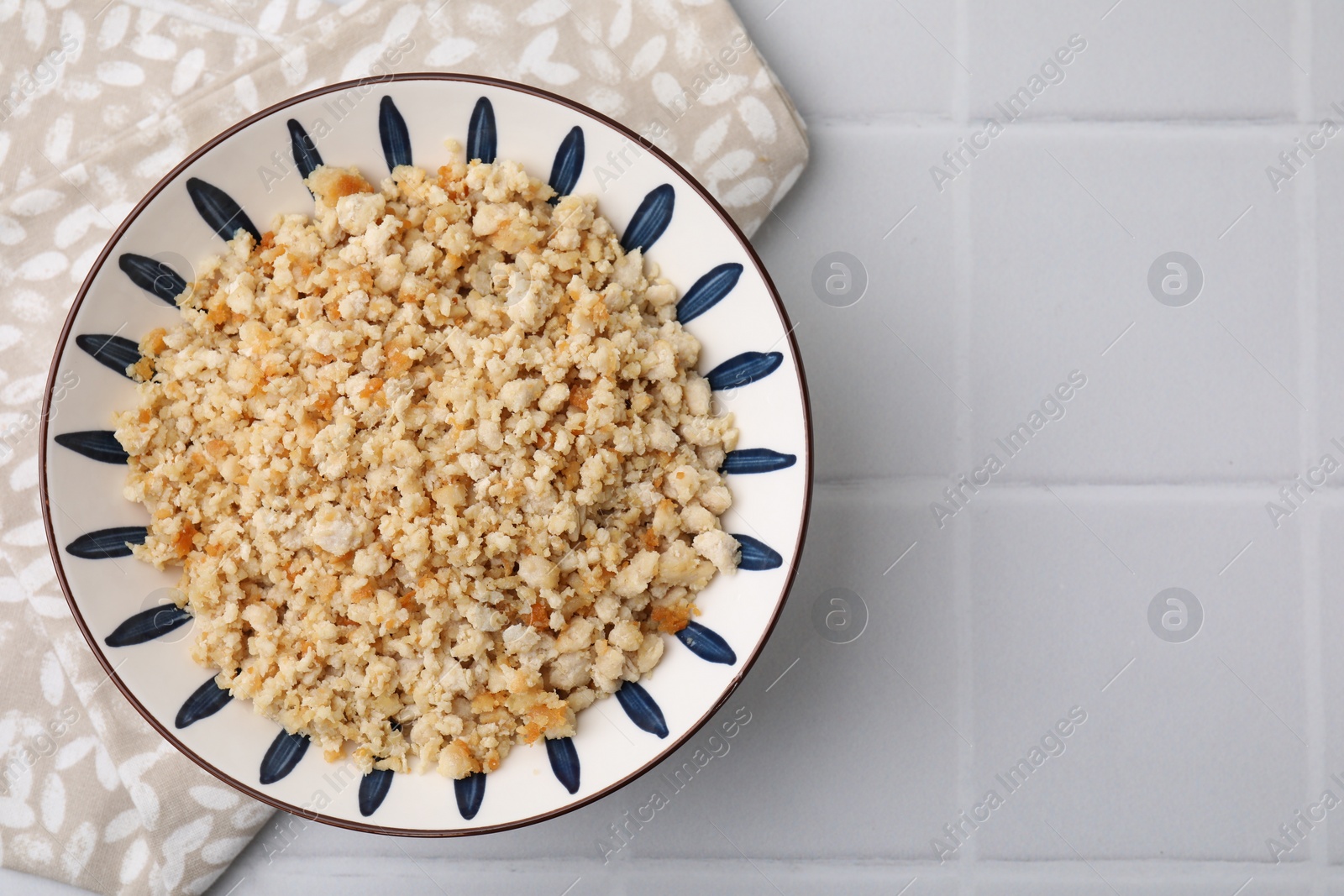 Photo of Fried ground meat in bowl on white tiled table, top view. Space for text